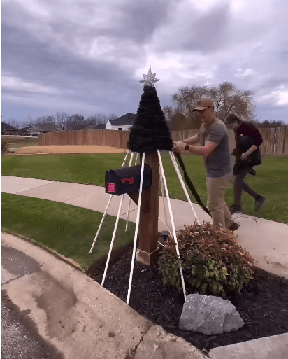 Man wrapping garland around the mailbox.